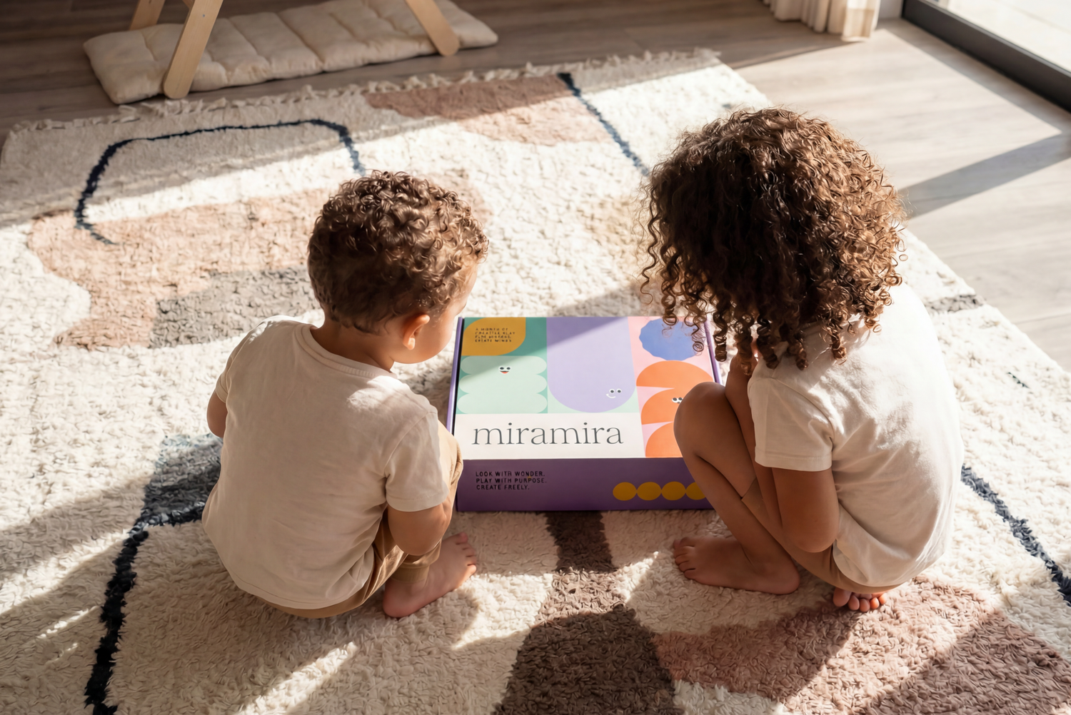 Two children sitting on a rug playing with a Miramira educational toy box.